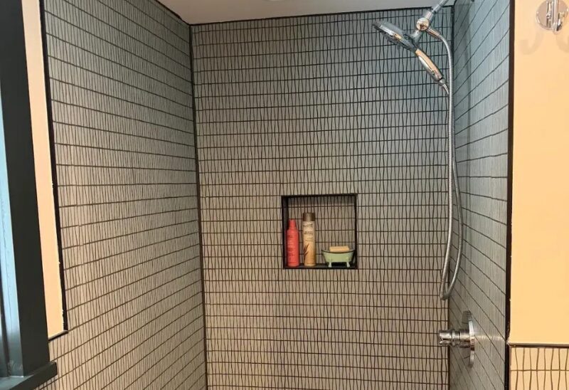 Tiled shower with built-in shelf and showerhead.