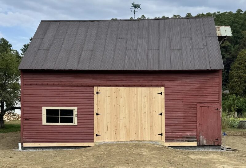 Red barn with wooden doors and window.