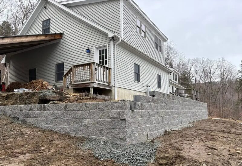 House with stone retaining wall and yard.