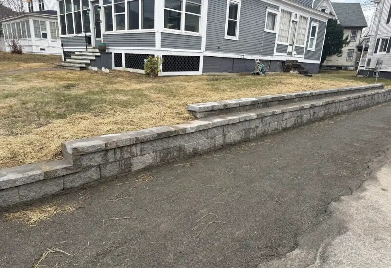 Gray retaining wall beside house and lawn.