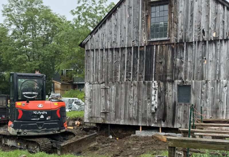 Excavator beside an old wooden building.