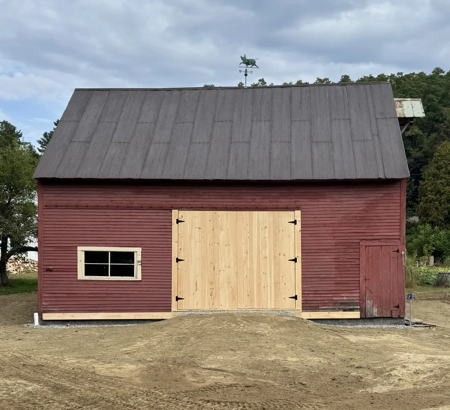 Red barn with wooden doors and window.